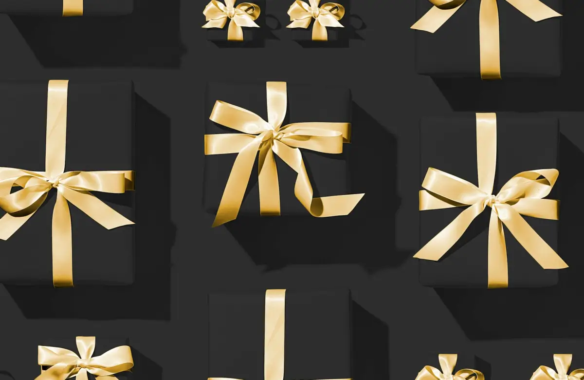 black gift boxes on a black surface wrapped with golden ribbon